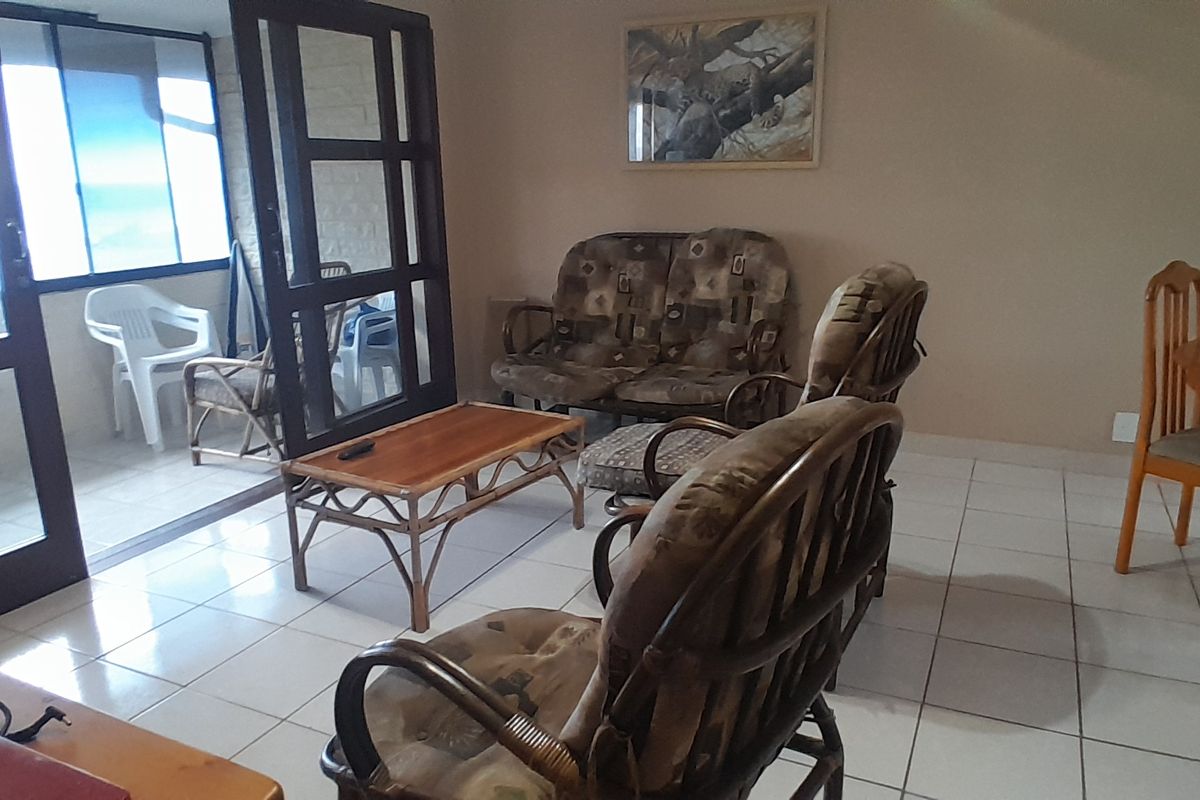 A spacious living area featuring tiled flooring and large sliding glass doors that provide access to an adjoining balcony and natural light.