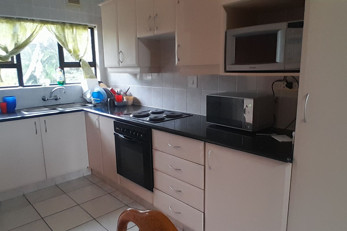A functional kitchen featuring built-in cabinetry, black granite countertops, an electric hob, built-in oven, and tiled flooring with a tiled backsplash.