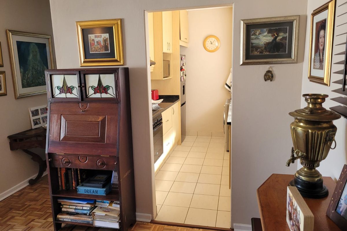 A view into a functional kitchen featuring tiled flooring, built-in cabinetry, and integrated cooking appliances, accessible from the adjacent living area.