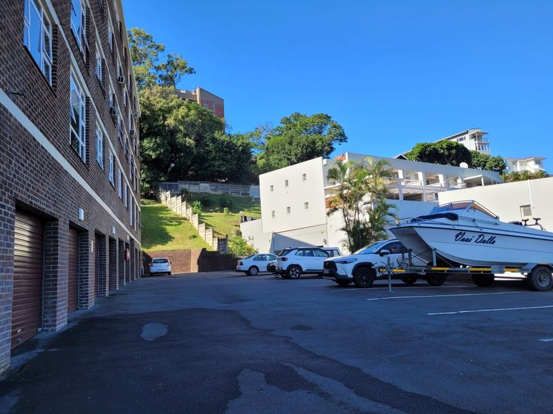 Exterior view of the apartment complex showing the rear parking area, brick facade, and access to garage units.