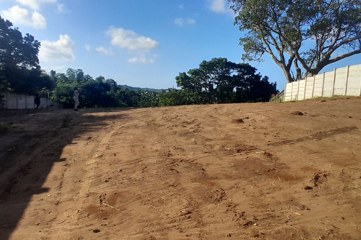 A vacant residential plot featuring cleared earth and established precast concrete boundary walls, ready for development.