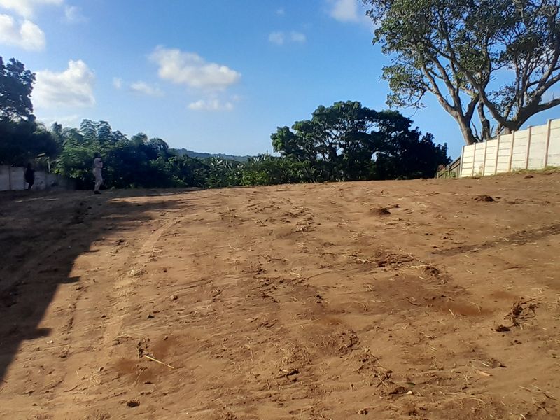 A vacant residential plot featuring cleared earth and established precast concrete boundary walls, ready for development.
