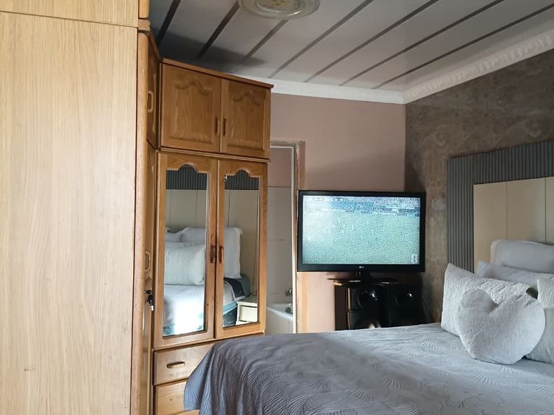 A bedroom featuring built-in wooden wardrobes, tiled flooring, and a paneled ceiling with decorative coving.