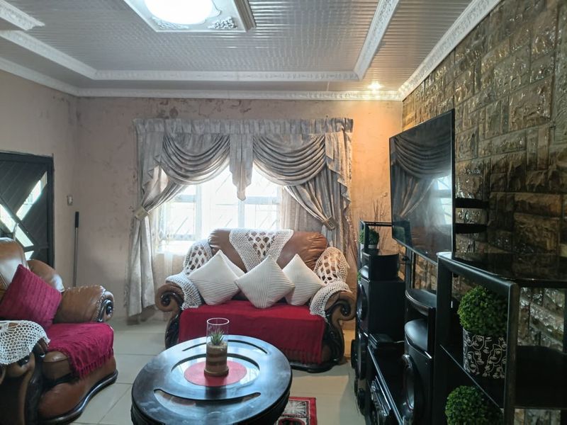 Living room featuring a stone accent wall, decorative ceiling tiles, and tiled flooring, currently requiring cosmetic wall repairs.