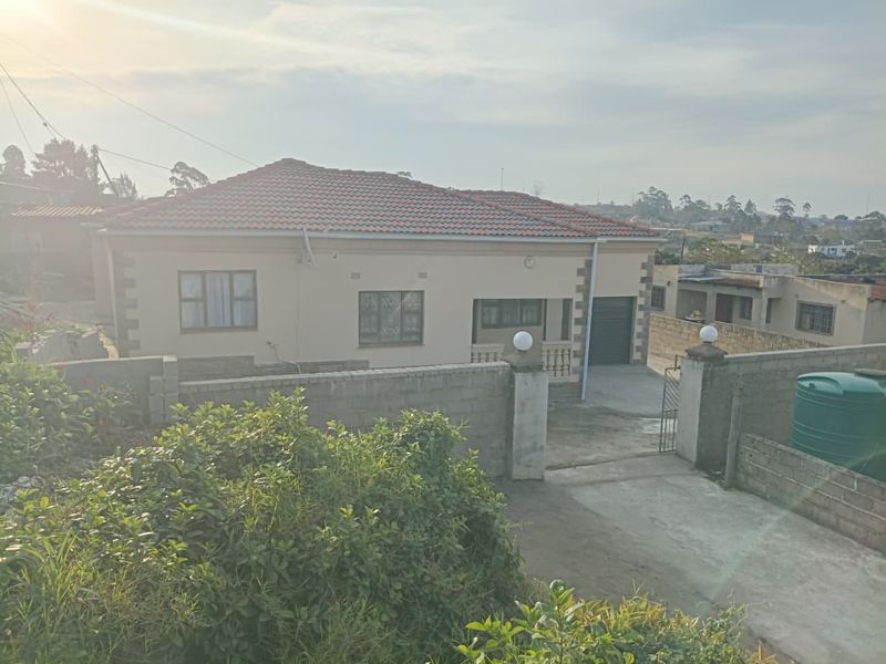 A well-maintained single-story residential home featuring a tiled roof, secure perimeter wall, and a paved driveway with an integrated garage.