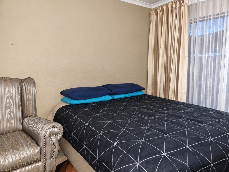 A bedroom featuring neutral wall tones, window with installed curtain rails, and space for a double bed.