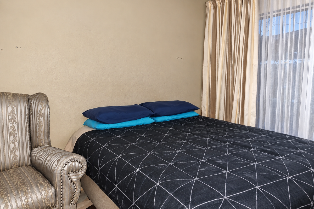 A bedroom featuring neutral wall tones, window with installed curtain rails, and space for a double bed.