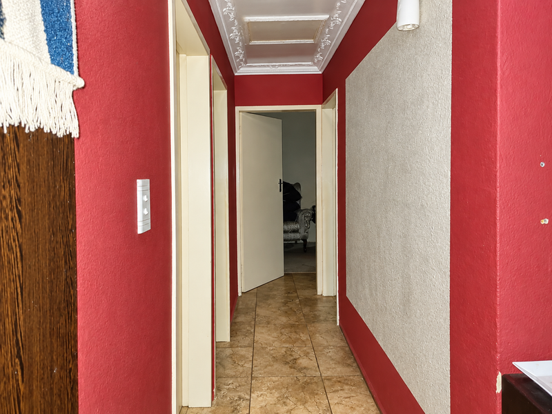 A functional hallway featuring tiled flooring and decorative ceiling cornicing, providing access to adjacent rooms.