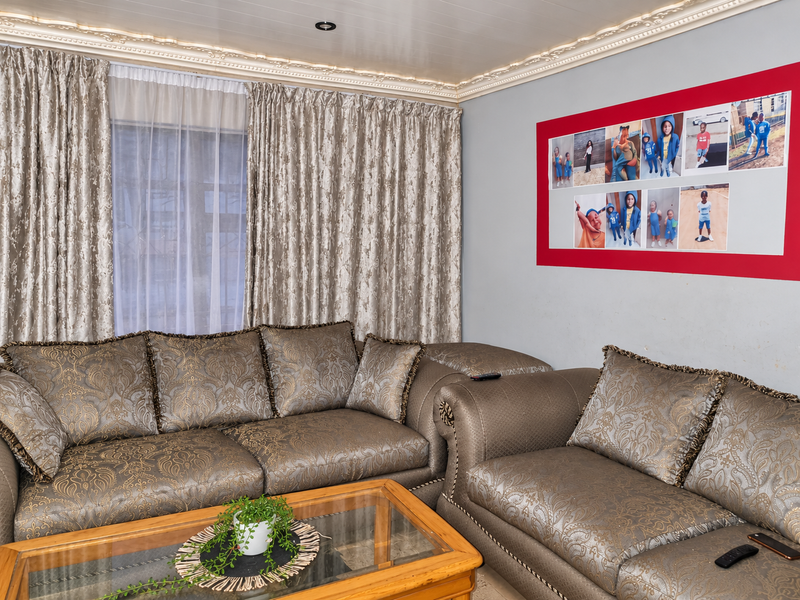 A comfortable living room featuring decorative ceiling cornicing, recessed downlighting, and a panelled ceiling finish.