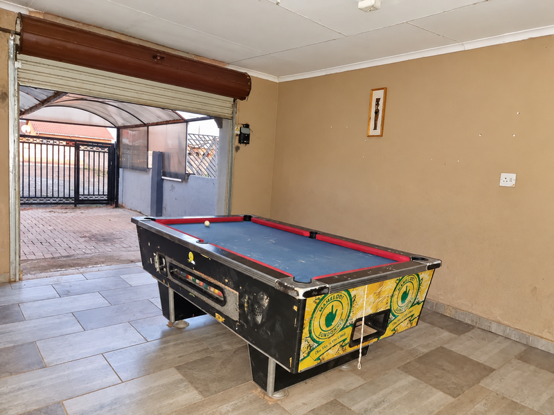 A functional garage space featuring tiled flooring and a roller shutter door, currently utilized as a recreational area.