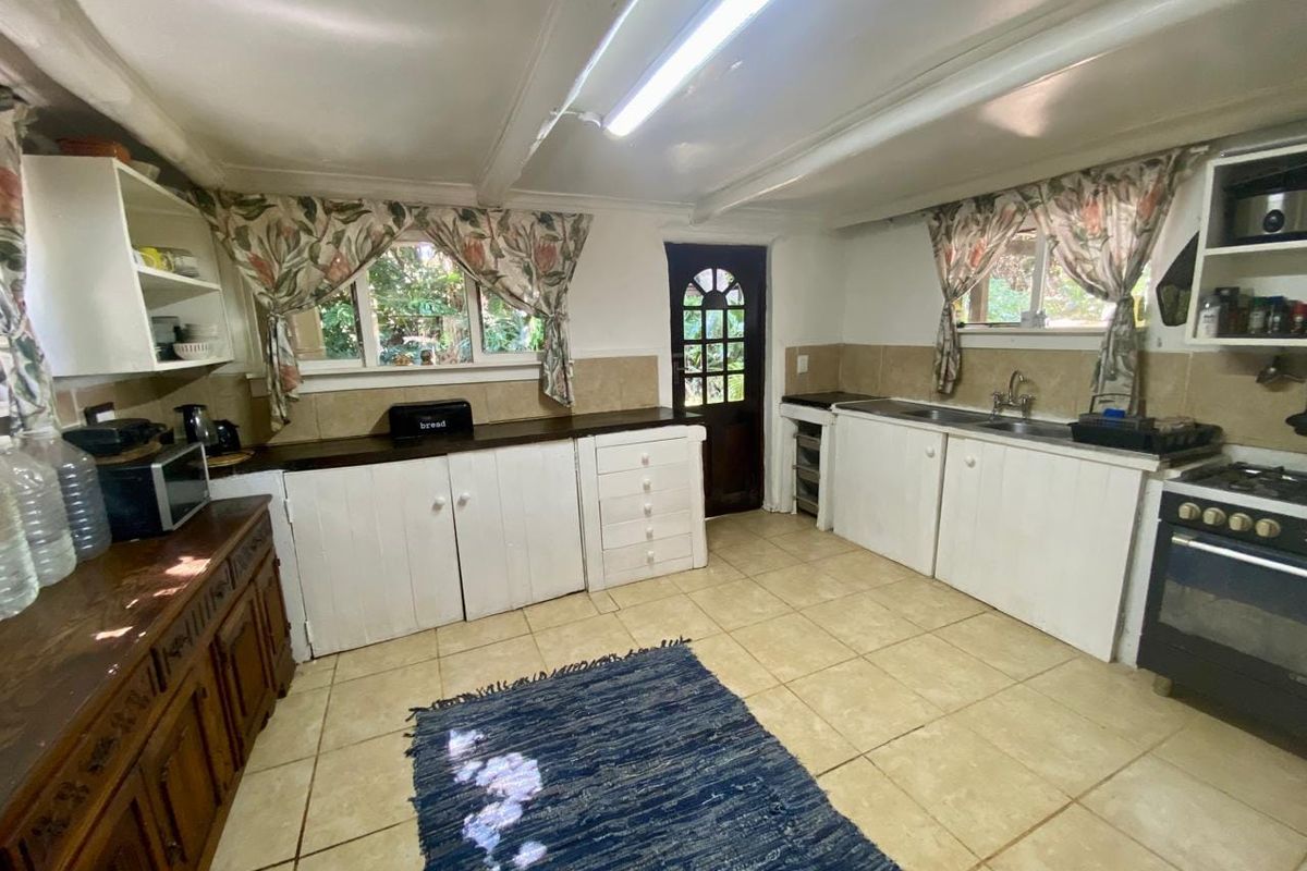 A dated kitchen featuring white cabinetry, tiled flooring, a double basin sink, and a freestanding oven, offering significant potential for modern renovation.