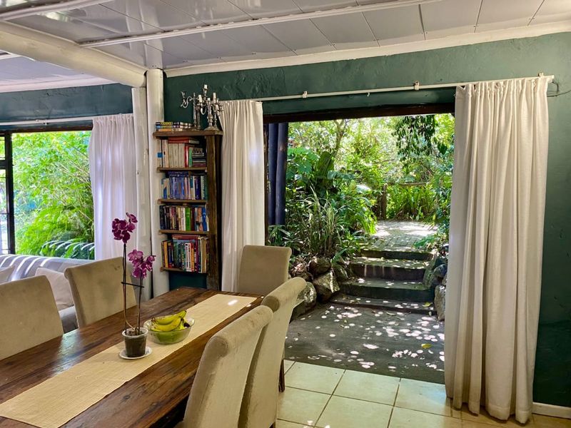 Dining area featuring tiled flooring and large sliding glass doors that provide direct access to a lush, landscaped garden.