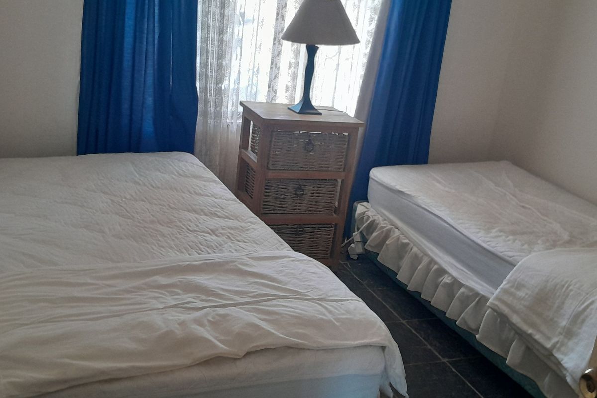 A compact bedroom featuring tiled flooring and a window with natural light, suitable for a guest room or children's bedroom.