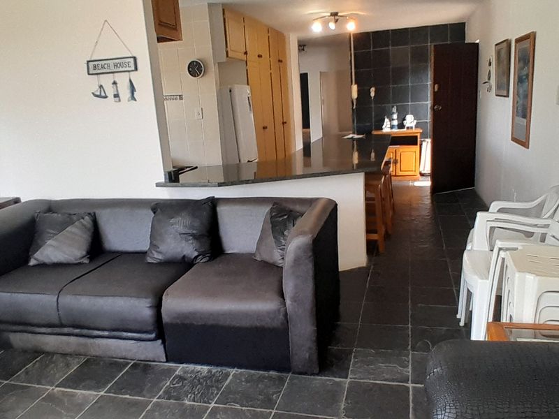 Open plan living and kitchen area featuring dark slate flooring and a granite breakfast bar, offering a functional layout for modern living.