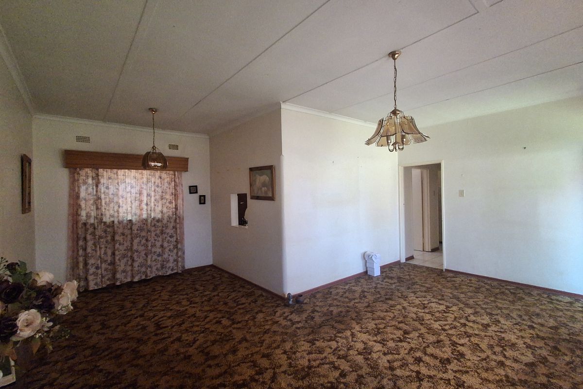 Spacious living area featuring dated carpet flooring and ceiling tiles, offering a blank canvas for renovation and modernization.