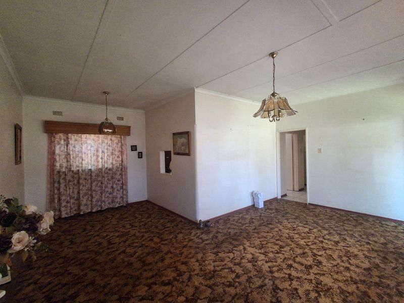 Spacious living area featuring dated carpet flooring and ceiling tiles, offering a blank canvas for renovation and modernization.