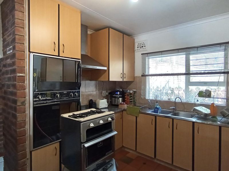 A functional kitchen featuring dated cabinetry, exposed brick accents, a double sink, and built-in oven, offering potential for a modern renovation.