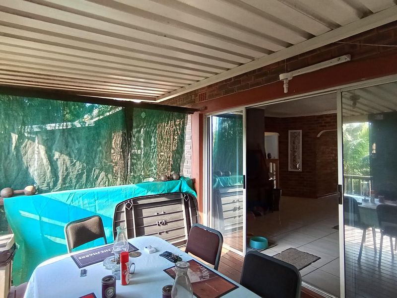 Covered patio area featuring a corrugated metal roof, brick walling, and sliding glass doors providing access to the interior living space.