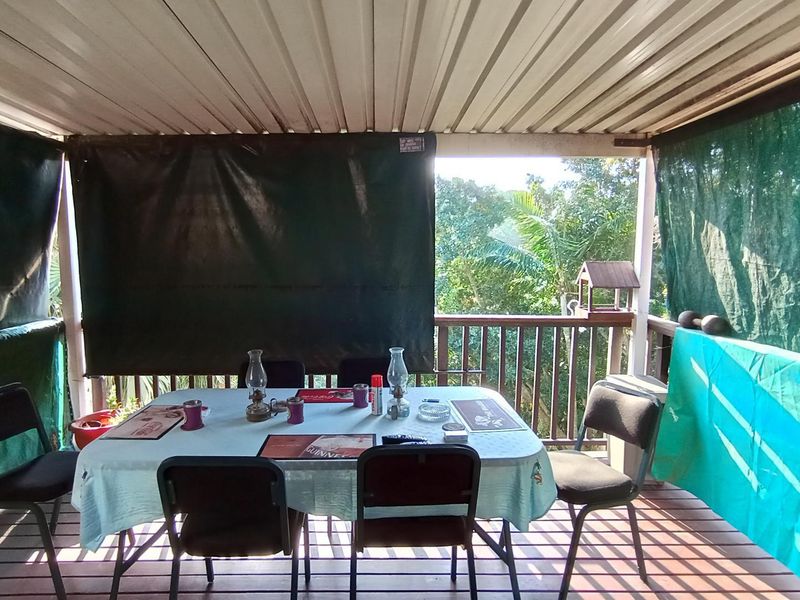 A covered outdoor patio area featuring timber decking, a corrugated metal roof, and timber balustrades, providing a functional space for outdoor dining.