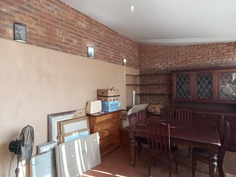 Dining room featuring exposed brick walls, built-in shelving, and wall-mounted lighting fixtures.