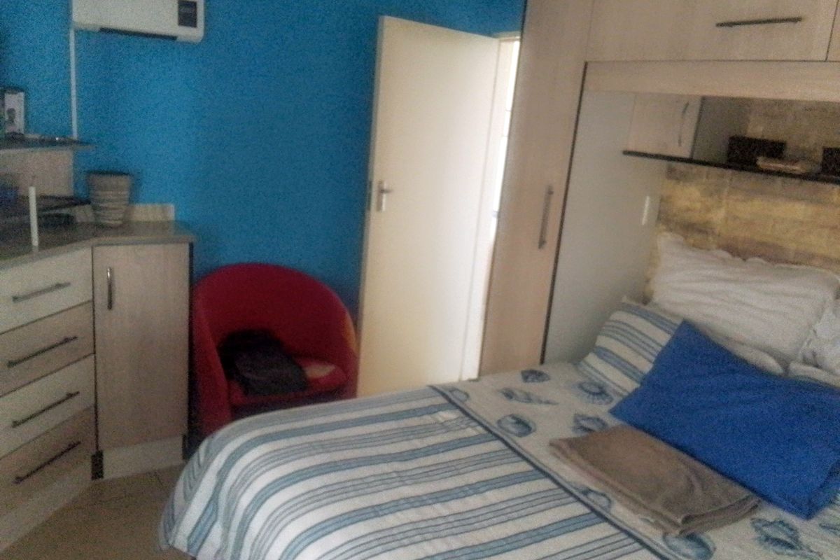 A bedroom featuring built-in cupboards, tiled flooring, and a wall-mounted split-system air conditioning unit.