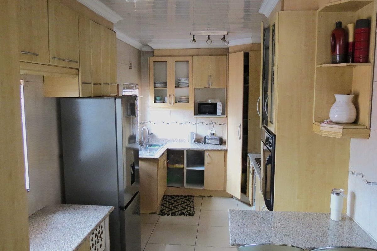 A functional kitchen featuring light wood cabinetry, granite countertops, tiled flooring, and built-in oven, offering potential for modernization and cosmetic updates.