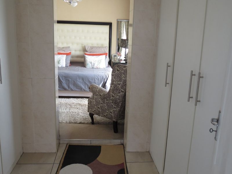 A functional hallway featuring built-in cupboards with modern handles and tiled flooring, providing a clean transition into the adjacent bedroom.