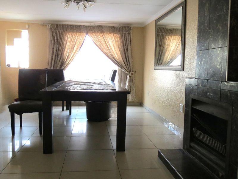 Dining area featuring tiled flooring, a built-in fireplace with dark tiling, and natural light from the window.
