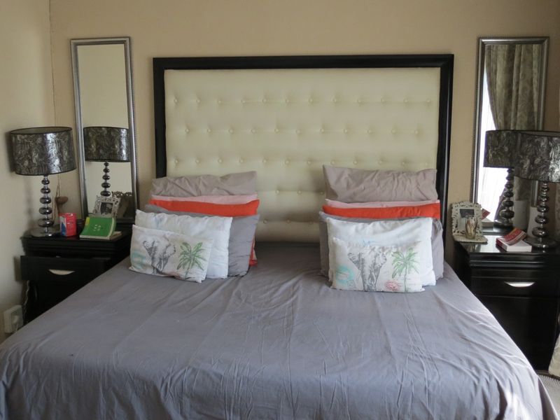 A bedroom featuring a tufted headboard and wall-mounted mirrors, providing a functional space for rest.