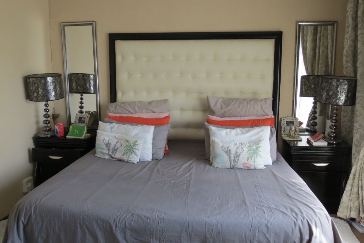 A bedroom featuring a tufted headboard and wall-mounted mirrors, providing a functional space for rest.