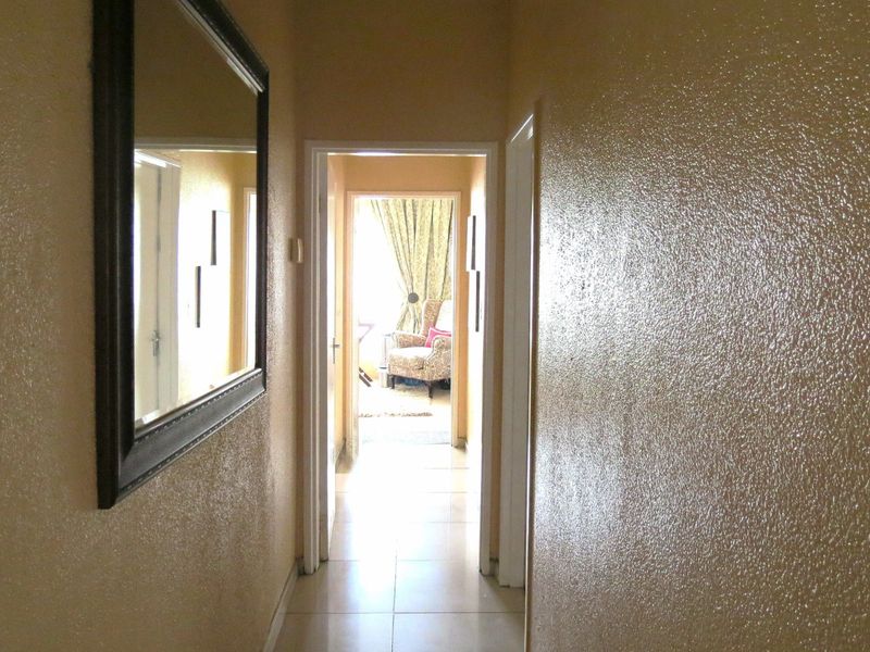 A simple interior hallway featuring tiled flooring and textured wall finishes, providing access to adjacent rooms.