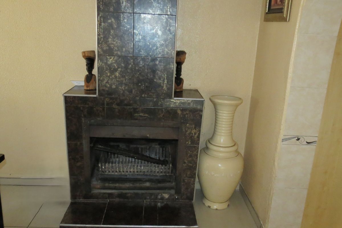 A living room featuring a built-in fireplace with dark decorative tiling and a matching hearth.