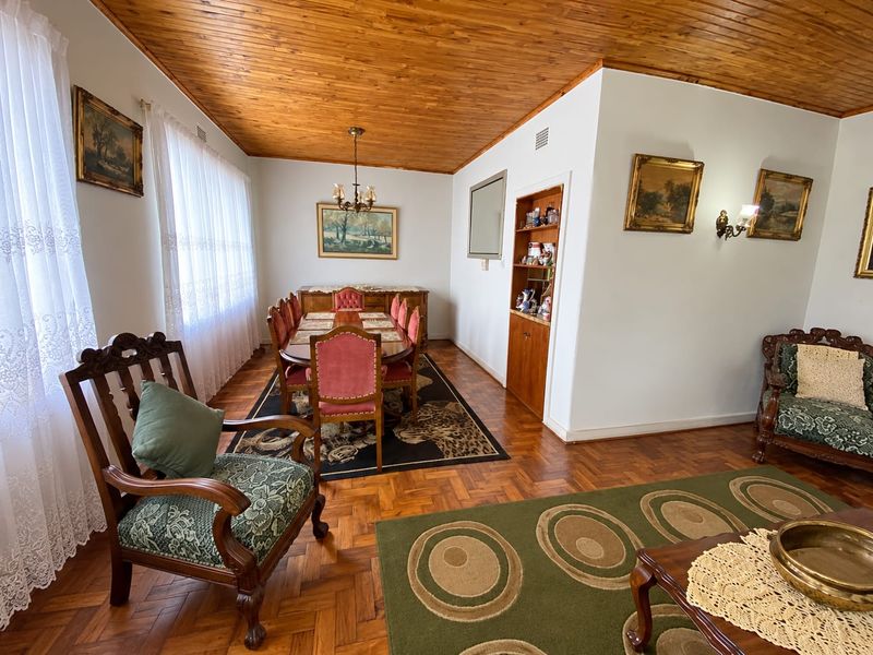 A formal dining area featuring warm timber ceilings, classic parquet flooring, and a built-in display cabinet, offering a traditional and well-maintained living space.