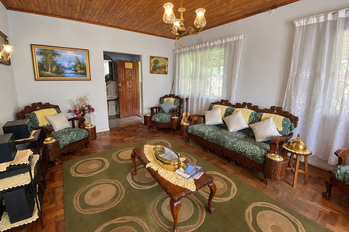 A traditional living room featuring warm parquet flooring, a timber tongue and groove ceiling, and a classic chandelier, offering a cozy and character-filled space.