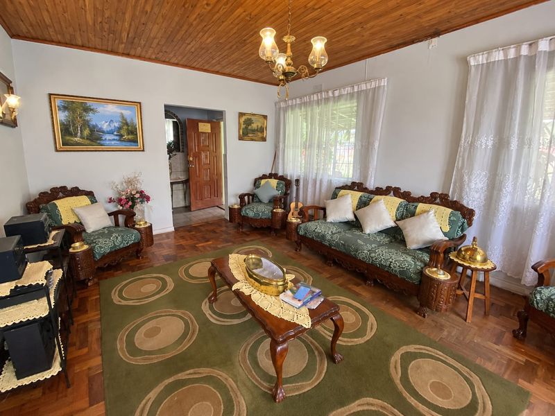 A traditional living room featuring warm parquet flooring, a timber tongue and groove ceiling, and a classic chandelier, offering a cozy and character-filled space.