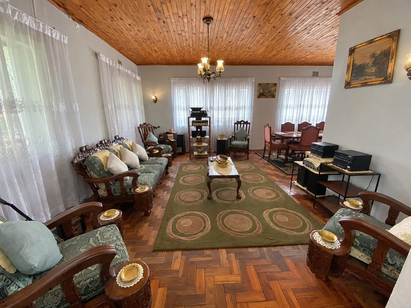 Spacious open-plan living and dining area featuring classic parquet flooring and a warm timber tongue and groove ceiling with traditional lighting fixtures.