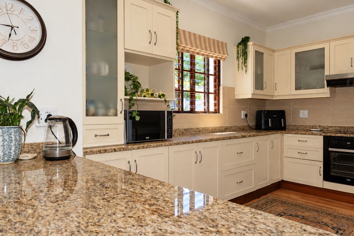 A well-maintained kitchen featuring cream cabinetry, granite countertops, a built-in oven, and an extractor fan, offering a functional and classic cooking space.