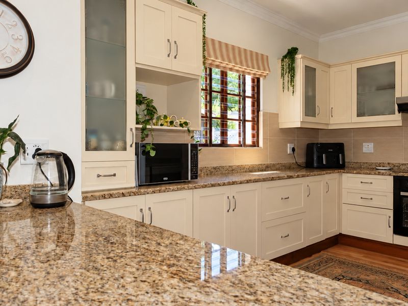 A well-maintained kitchen featuring cream cabinetry, granite countertops, a built-in oven, and an extractor fan, offering a functional and classic cooking space.