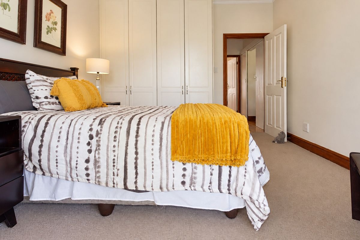 A well-maintained bedroom featuring neutral carpeting, built-in cupboards, and classic timber door frames, offering a clean and functional living space.