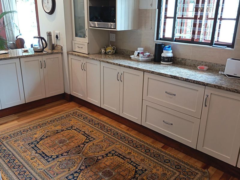 A well-maintained kitchen featuring light-toned cabinetry, granite countertops, and hardwood flooring, offering a clean and functional workspace.