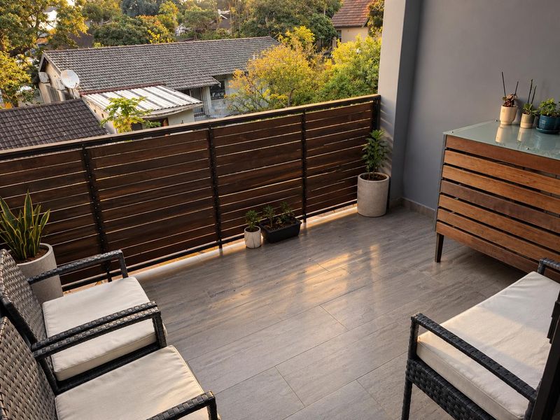 A well-maintained balcony featuring modern timber slat balustrades and durable tiled flooring, offering a pleasant outdoor space with neighbourhood views.