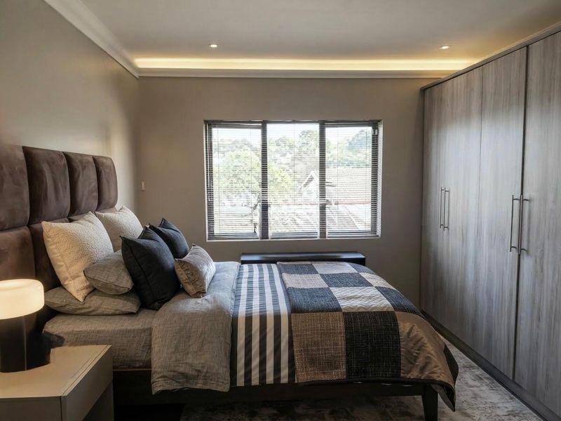 A well-appointed bedroom featuring modern built-in cupboards, recessed ceiling lighting, and venetian blinds, offering a clean and contemporary living space.