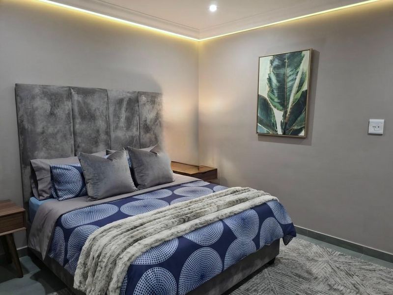 A well-maintained bedroom featuring modern recessed cove lighting and neutral wall finishes, creating a comfortable and contemporary sleeping space.