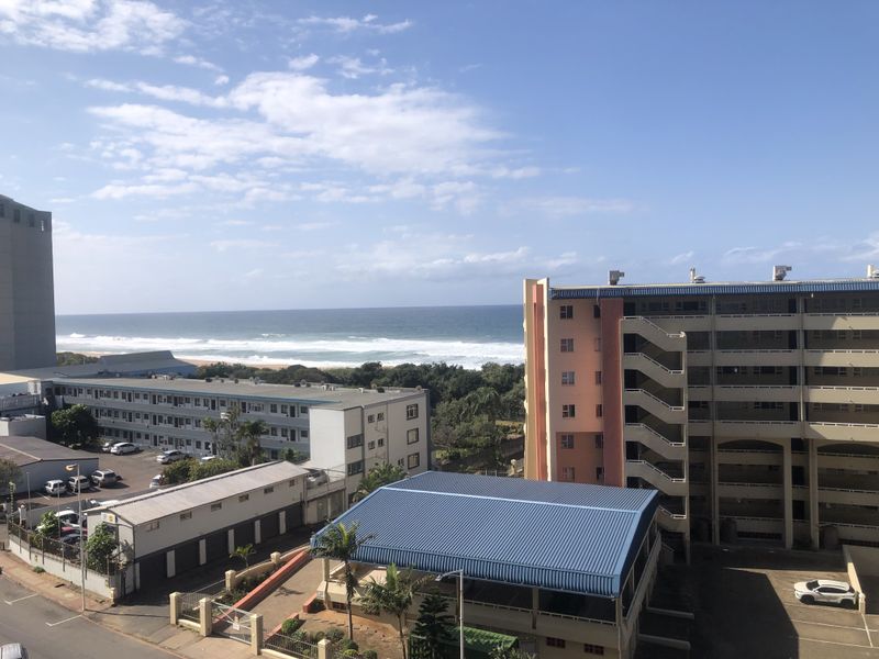 An elevated view overlooking the surrounding residential buildings with a clear outlook towards the ocean and coastline.