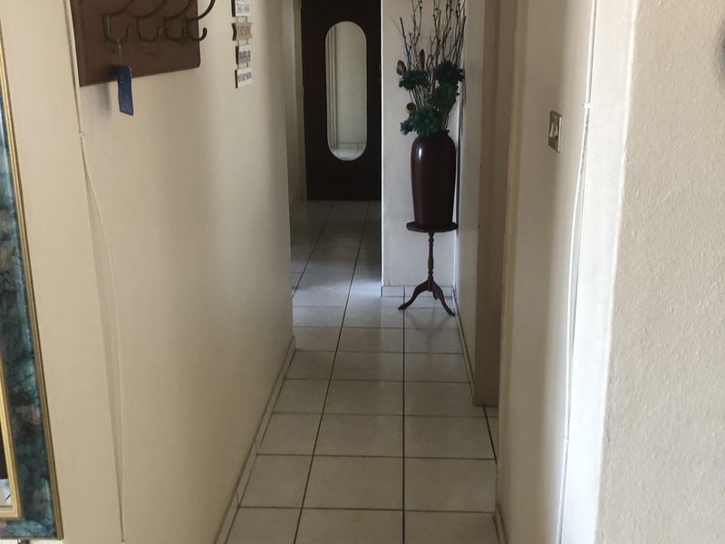 A functional hallway featuring neutral wall finishes and ceramic floor tiles, providing access to the interior living spaces.