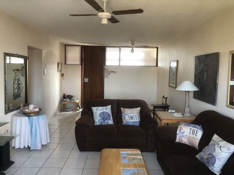 A living room featuring tiled flooring, ceiling fans, and natural light through horizontal blinds, offering a functional space with potential for modern updates.