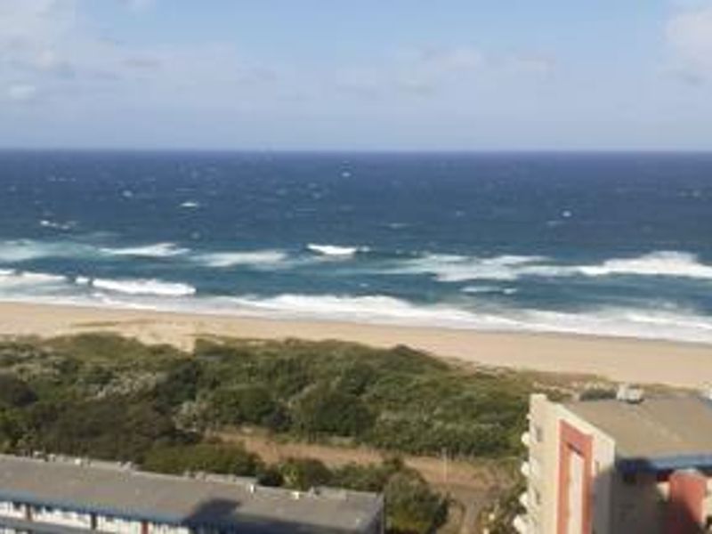 A scenic elevated view overlooking the coastline, sandy beach, and ocean from the apartment.