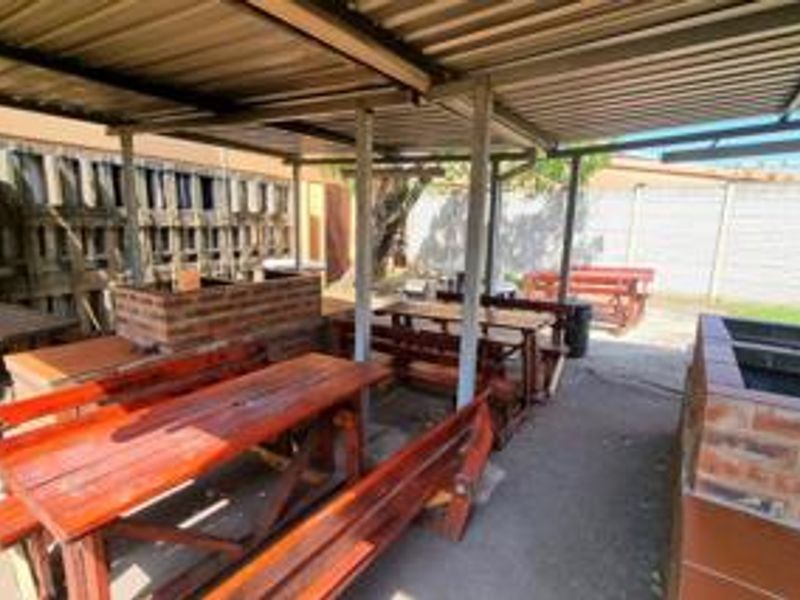 Covered outdoor entertainment area featuring built-in brick braai facilities, concrete flooring, and a corrugated metal roof structure.