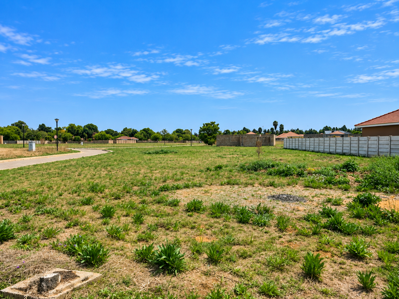 A vacant residential plot featuring a precast concrete boundary wall, street access, and established street lighting in a developed neighborhood setting.