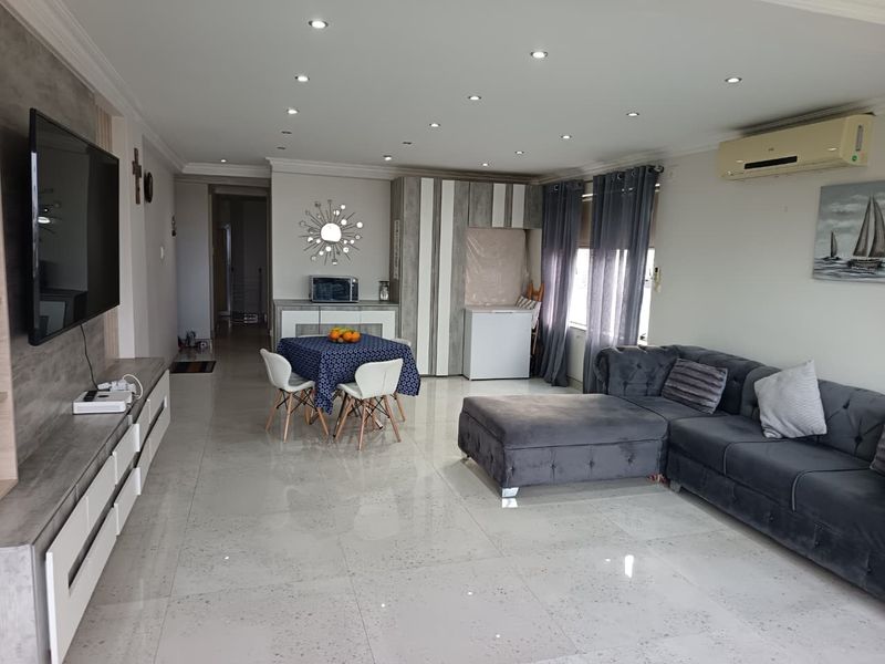 Spacious open-plan living and dining area featuring polished porcelain floor tiles, recessed downlighting, and integrated air conditioning.